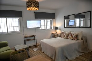 Ein Schlafzimmer mit Bett, Fernseher, Schreibtisch, Stuhl und Lampe.