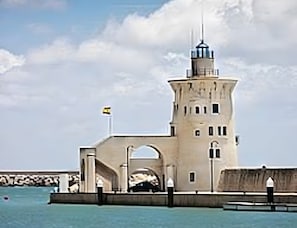 A lighthouse with a tower and a smaller building, connected by a bridge over water. - Studio Apartment No.2 – Comfort and Style in El Puerto de Santa María (El Puerto de Santa María)