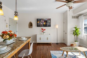 A modern kitchen with a granite countertop, white cabinetry, and a dining area with a table and chairs.