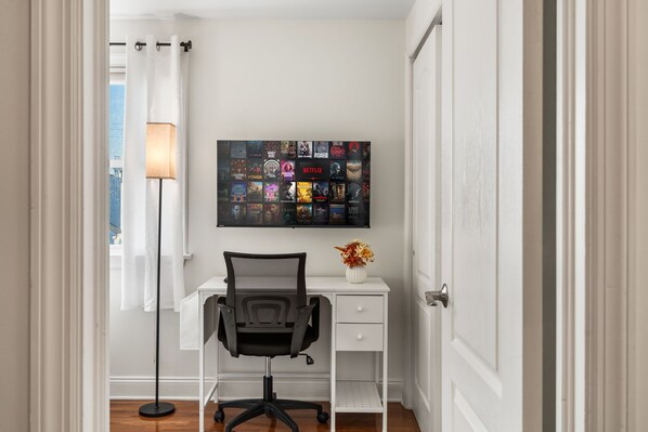 Una habitación con escritorio, silla, lámpara y una pared con carteles de películas.