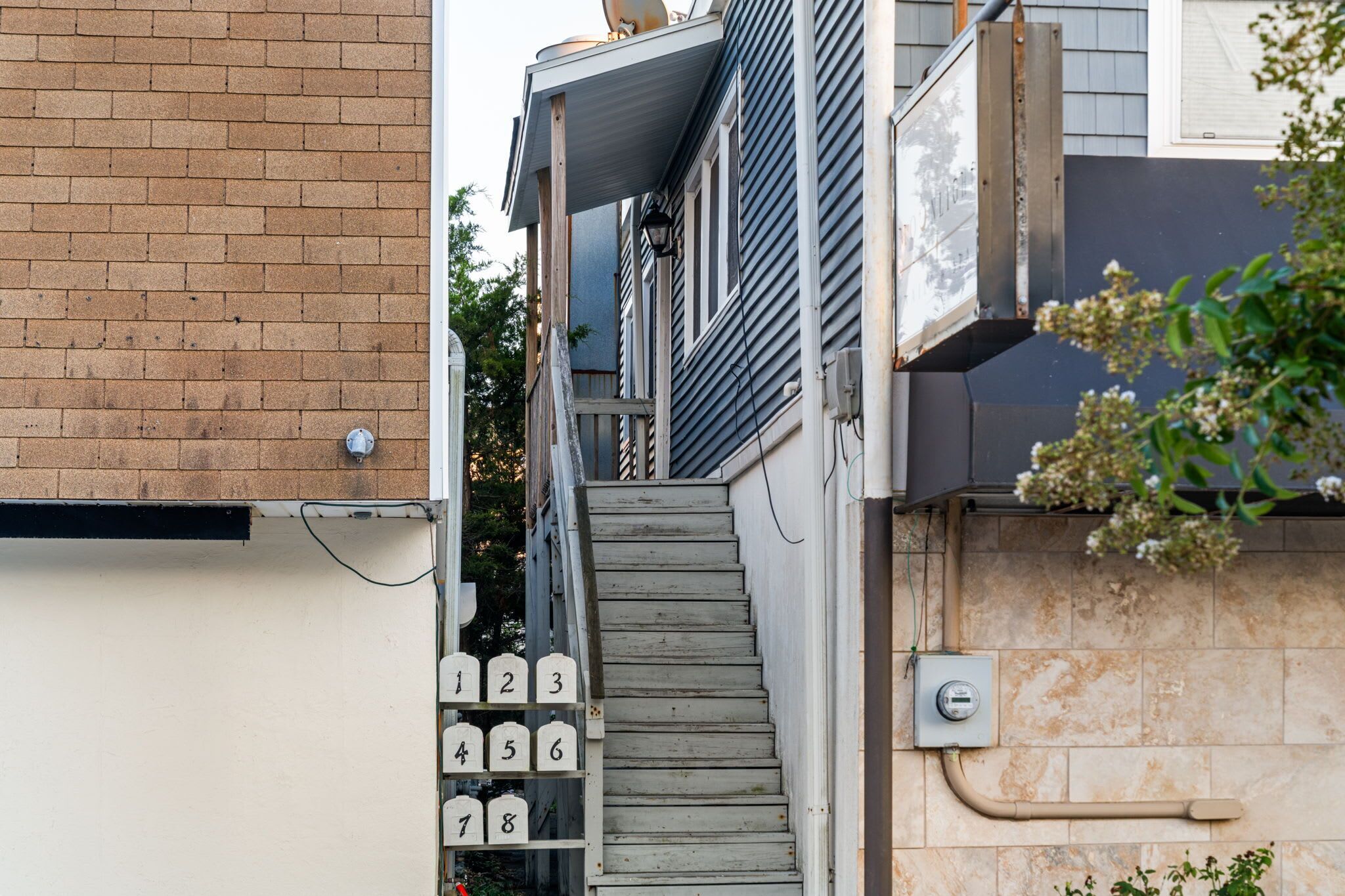 A narrow stairway leading to a landing with mailboxes numbered 1 to 8.