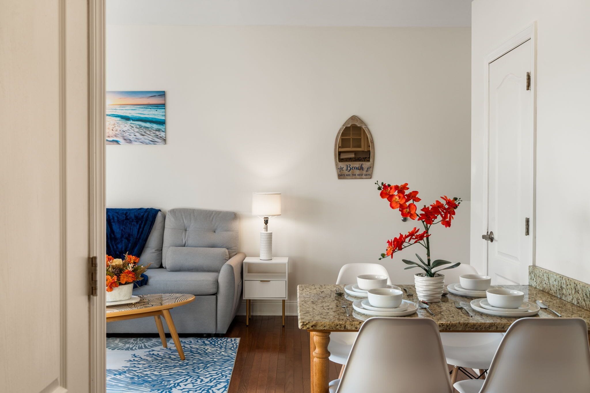 Een woonkamer met een bank, een salontafel, en een eethoek met een tafel voor vier personen.