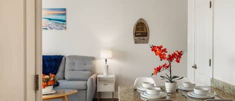 Een woonkamer met een bank, een salontafel, en een eethoek met een tafel voor vier personen.