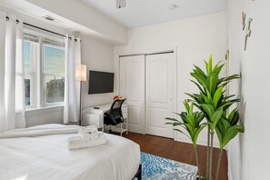 A hotel room with a bed, a desk, a chair, a TV, and a plant. - Breezy Beach Getaway, 3 Min Walk to Beach (Brigantine)
