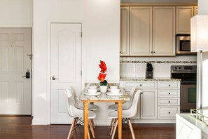 A kitchen with white cabinets, a marble countertop, and a dining table with chairs. - Breezy Beach Getaway, 3 Min Walk to Beach (Brigantine)