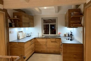 A kitchen with wooden cabinets, a countertop, and a window. - Holiday apartment with 1 bedroom (Sankt Andreasberg)