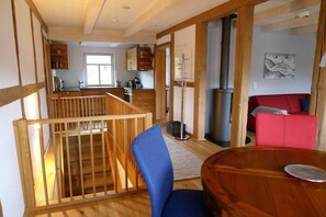 A spacious living area with a wooden staircase, a dining table, and a red sofa. - Holiday apartment with 1 bedroom (Sankt Andreasberg)