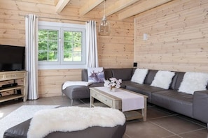 A modern living room with a sofa, a coffee table, and a television. - Mountain Forest Lodge Time Out (Schierke)