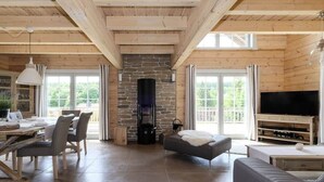 Amplia sala de estar con chimenea de piedra, televisor y comedor con mesa y sillas de madera.