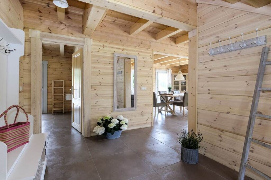 A wooden interior with a dining area, a mirror, and a staircase.
