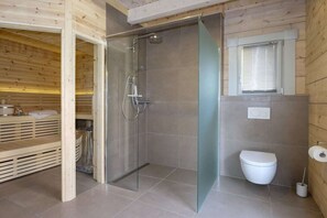 Ein modernes Badezimmer mit Duschkabine aus Glas, Toilette und einem Fenster mit Jalousien.