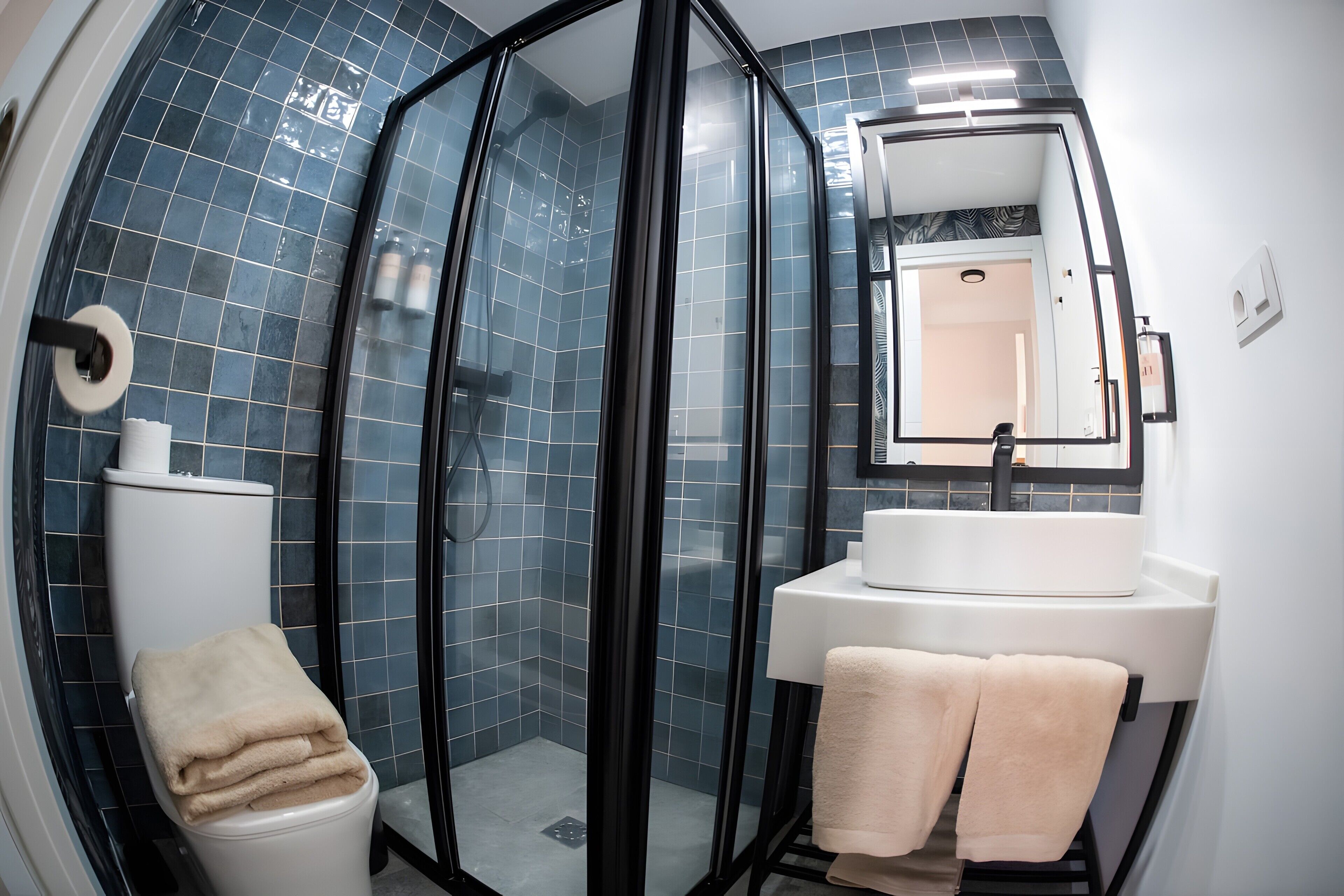 Ein modernes Badezimmer mit einer gläsernen Duschkabine, einem weißen Waschbecken und einer Toilette.