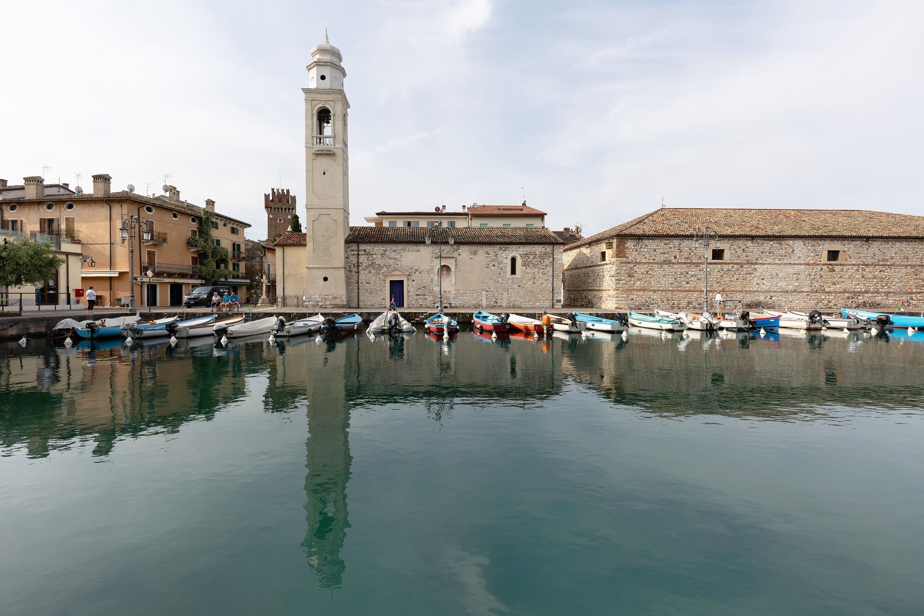 A waterfront with boats docked, a tower, and historic buildings.