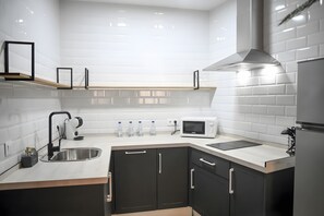 A modern kitchen with a stainless steel sink, a microwave, and a built-in oven. - Deluxe Apartment No. 1 – Charm and Comfort in El Puerto de Santa María (El Puerto de Santa María)