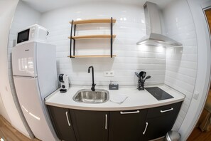 Cozinha compacta com geladeira embutida, pia e micro-ondas.