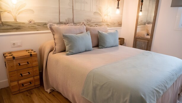A bedroom with a bed, a chest of drawers, a mirror, and a wall painting. - Deluxe Apartment No.1 – Charm and Comfort in El Puerto de Santa María (El Puerto de Santa María)