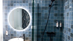 A bathroom with a round mirror, a white sink, and a shower area with a handheld showerhead. - Deluxe Apartment No.1 – Charm and Comfort in El Puerto de Santa María (El Puerto de Santa María)