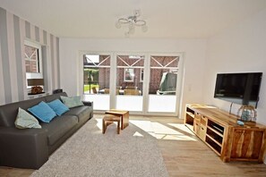 A living room with a sofa, a coffee table, a TV, and a wooden cabinet. - favorite spot by the sea (Norden-Norddeich)