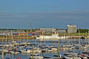A marina with multiple boats docked, a large cruise ship, and buildings in the background. - favorite spot by the sea (Norden-Norddeich)