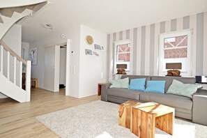 A modern living room with a grey sofa, wooden coffee table, and striped wallpaper. - favorite spot by the sea (Norden-Norddeich)