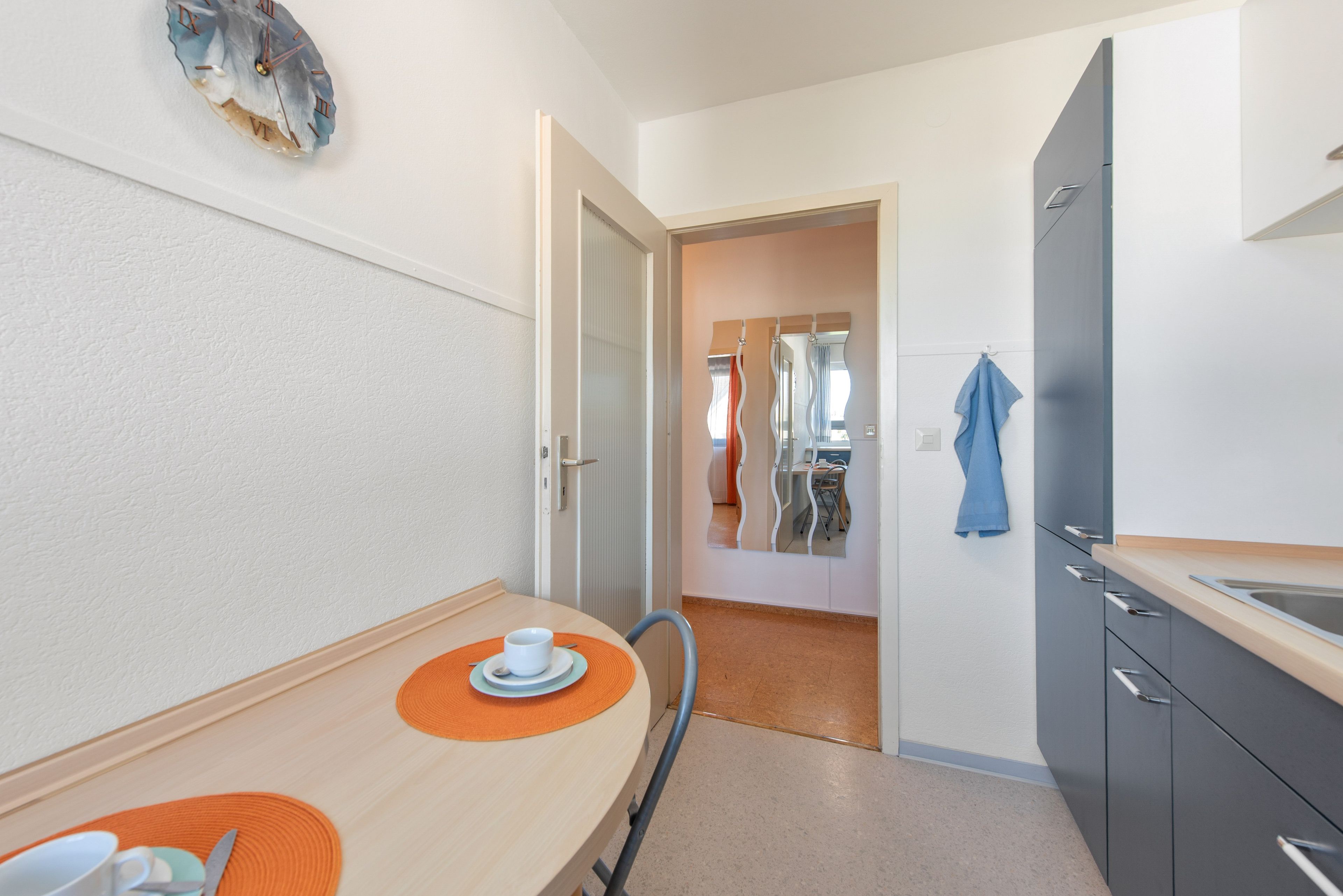 Een kleine keuken met een eethoek, een koelkast en een spiegel.