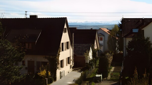 En bostadsgata med hus, en klar himmel och avlägsna berg.