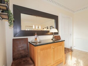 Une pièce comprenant un meuble en bois, un miroir, une lampe et une chaise.