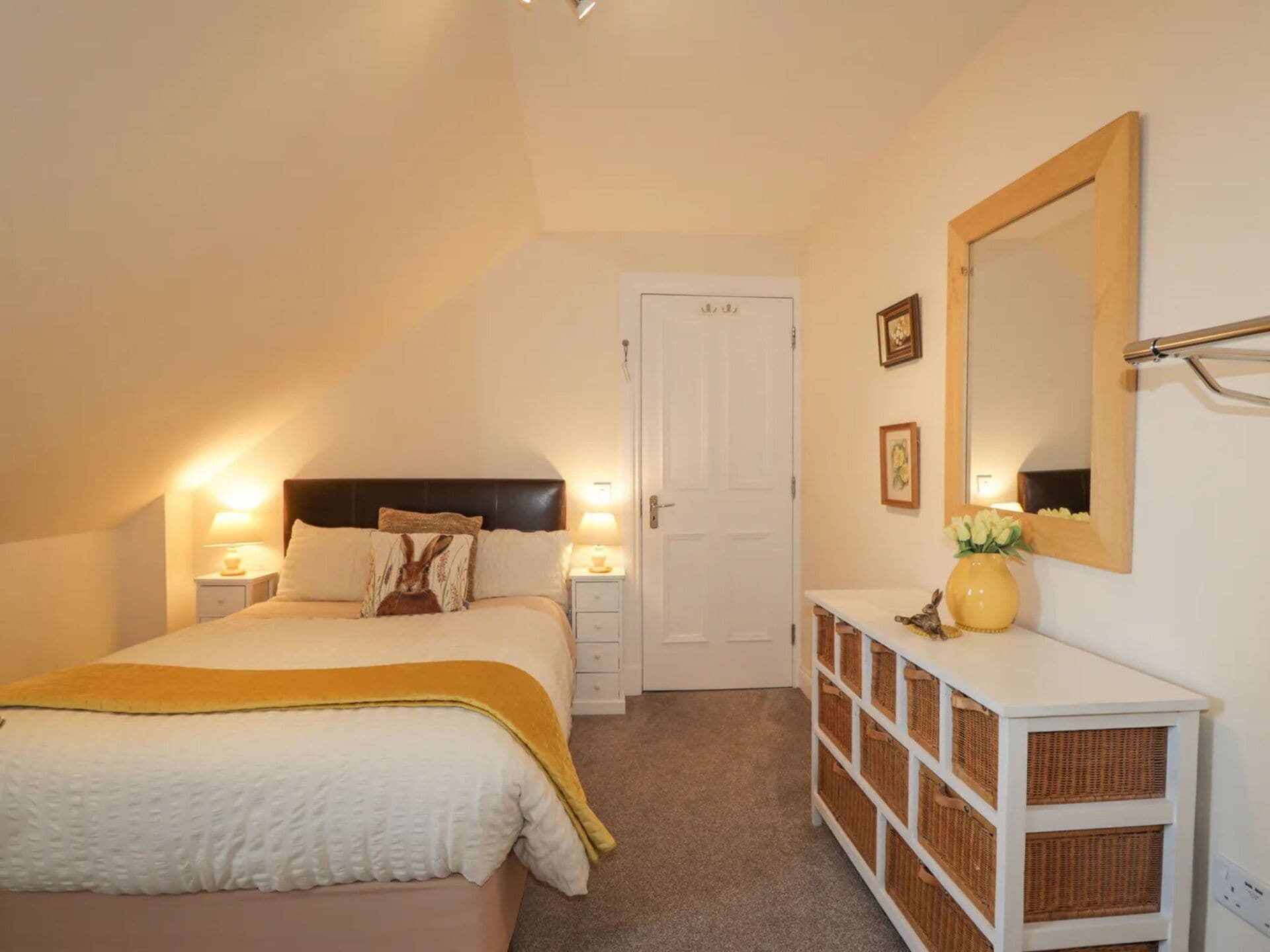 A bedroom with a bed, bedside tables, a dresser, a mirror, and a door.