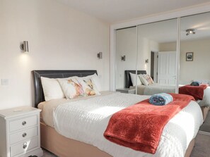 Een slaapkamer met een bed, nachtkastjes, een spiegel en een kledingkast.
