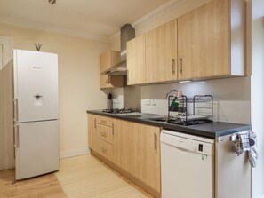 Eine moderne Küche mit Holzschränken, einem eingebauten Geschirrspüler und einem Gasherd.