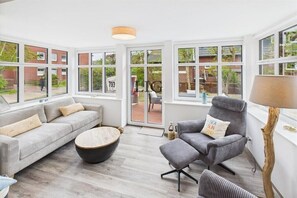 Un salon moderne avec un canapé, un fauteuil et une table basse ronde.