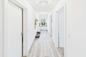 A hallway with white walls, a wooden floor, and a door with the text 'LIG' on it. - Holiday apartment Norderloog 3 (Langeoog)
