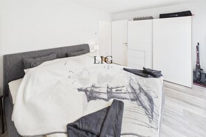 A bedroom with a bed, a wardrobe, and a desk with a lamp. - Holiday apartment Norderloog 3 (Langeoog)