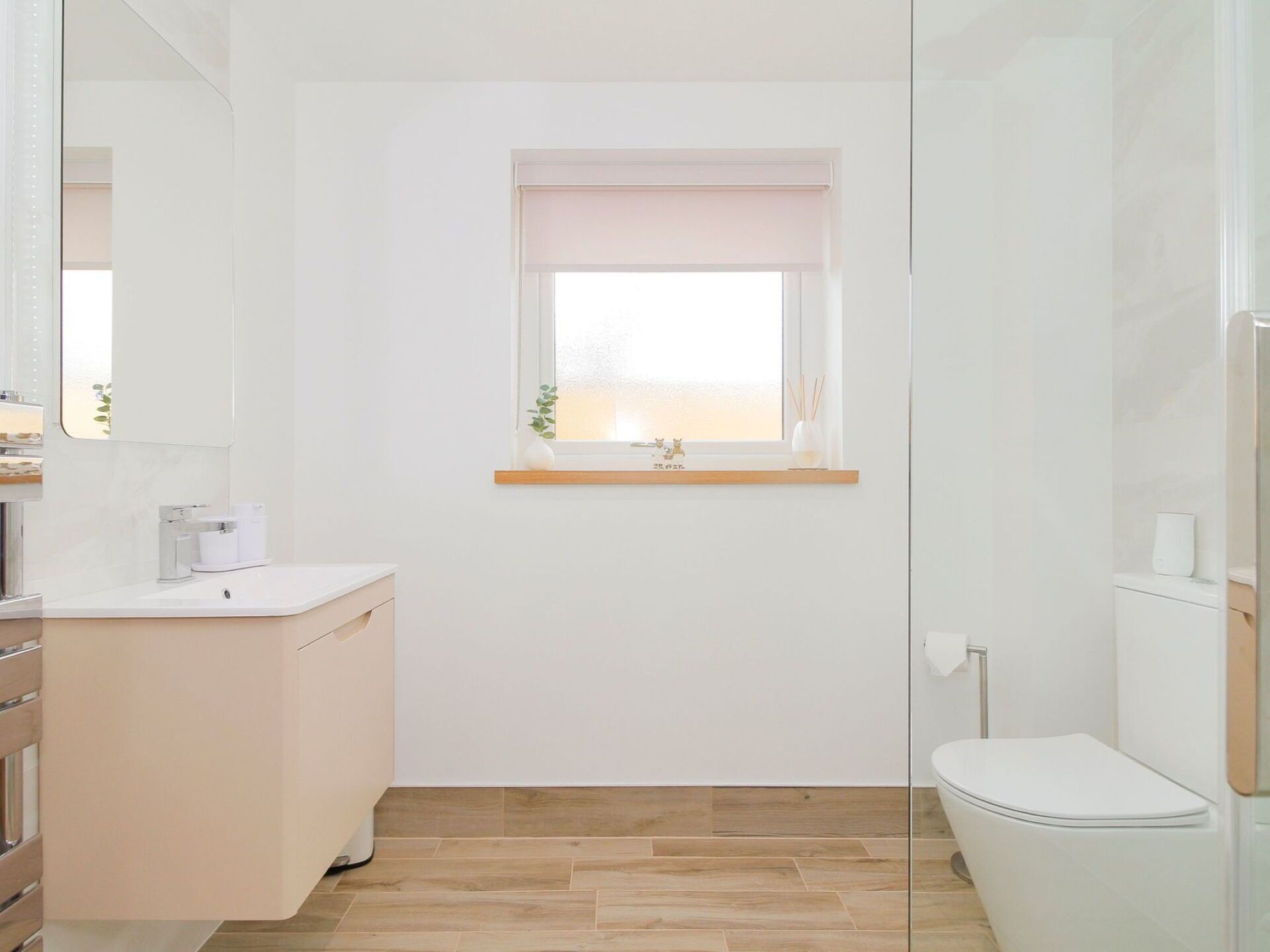 Een kleine, schone badkamer met toilet, wastafel en raam.