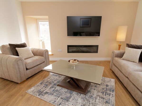 Ein Wohnzimmer mit zwei Sofas, einem Couchtisch, einem Flachbildfernseher und einem Kamin.