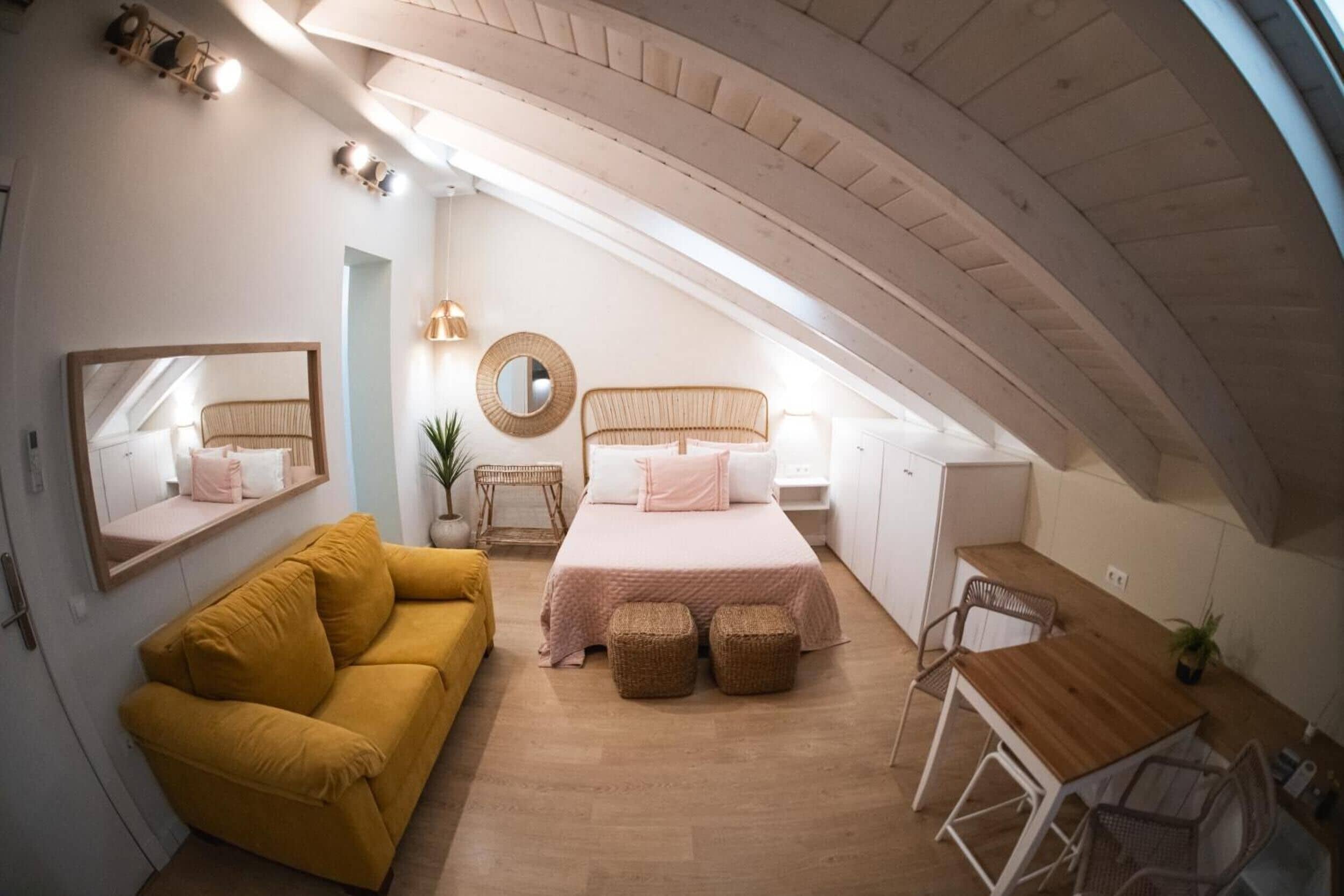 Quarto com cama, sofá, escrivaninha e cadeira.
