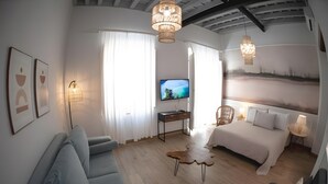 A modern hotel room with a bed, a desk, a television, and a seating area. - Cozy Studio with All Amenities in One Space (El Puerto de Santa María)