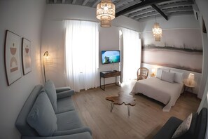 Une chambre d’hôtel moderne équipée d’un lit, d’un bureau, d’une télévision et d’un coin salon.
