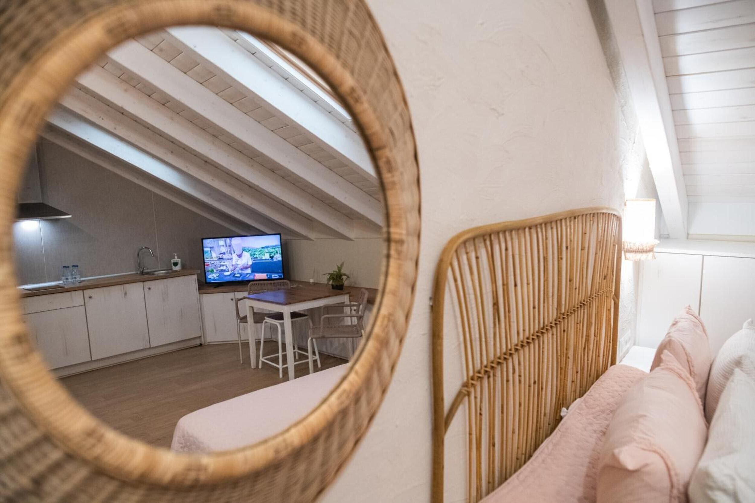 Une chambre de style loft moderne avec un plafond en pente, un coin repas avec un téléviseur et une cuisine en arrière-plan.