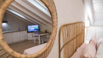 Une chambre de style loft moderne avec un plafond en pente, un coin repas avec un téléviseur et une cuisine en arrière-plan.