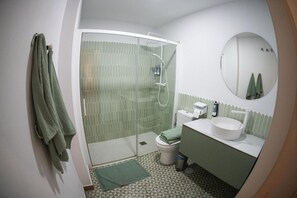 Une salle de bain équipée d’une douche, de toilettes, d’un lavabo et d’un miroir.