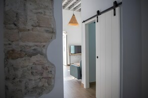 A hallway with a stone wall, a sliding barn door, a hanging pendant light, and a glimpse of a room with a desk and chair. - Cozy studio with all amenities in one space (El Puerto de Santa María)