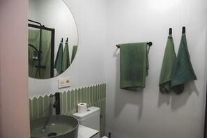 A bathroom with a round mirror, a sink, a toilet, and towels hanging on a rack. - Superior Comfortable and Functional Apartment (El Puerto de Santa María)