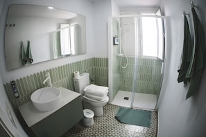 Une salle de bain avec un lavabo blanc, des toilettes et un espace douche.