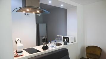 Een moderne kamer met een bureau, een stoel, een magnetron, een waterdispenser en een koffieapparaat.