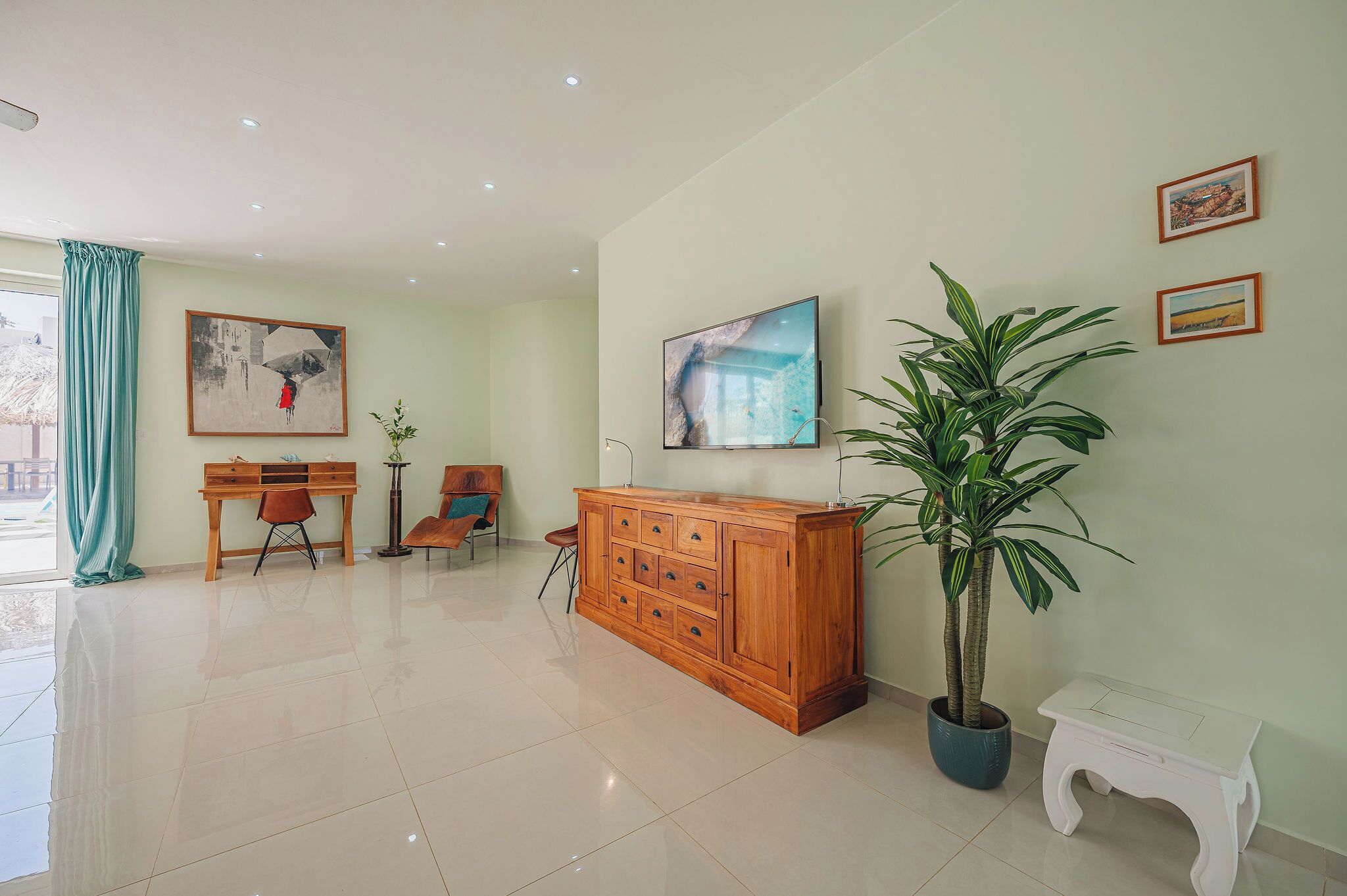 A spacious room with a wooden cabinet, a potted plant, and artwork on the walls.