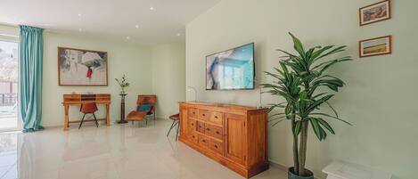 A spacious room with a wooden cabinet, a potted plant, and artwork on the walls.