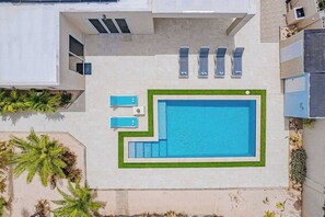 Ein Luftbild zeigt einen Swimmingpool mit mehreren Liegestühlen und einer kleinen Gartenanlage.