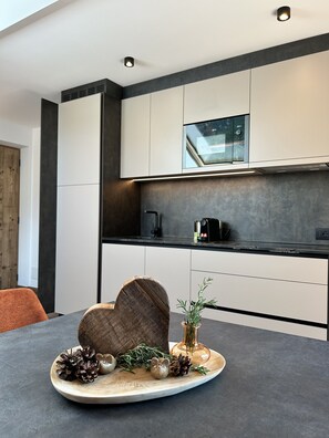 A modern kitchen with white cabinets, a black countertop, and a built-in oven. - Apartment "Seiser Alm" with Mountain View, Shared Garden and Wi-Fi (Passua)