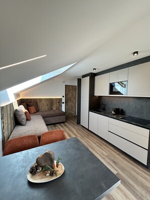 A modern kitchen with a built-in oven and microwave, a dining area with a table and chairs, and a cozy seating area with a sofa and cushions. - Apartment "Seiser Alm" with Mountain View, Shared Garden and Wi-Fi (Passua)